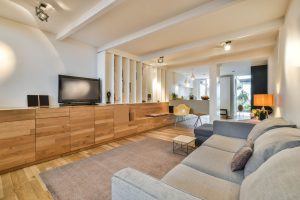 Modern living room with matching wood flooring, custom cabinetry, and coordinated interior finishes, showcasing a completed home reconstruction after renovation.